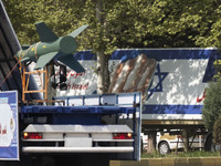 A truck is carrying an Iranian-made Qased bomb past an anti-Israeli billboard during a military parade marking Iran's Army Day anniversary a...