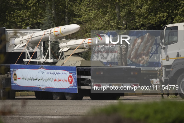 A truck is carrying Iranian-made Sayyad-4B missiles past an anti-Israeli billboard during a military parade marking the anniversary of Iran'...