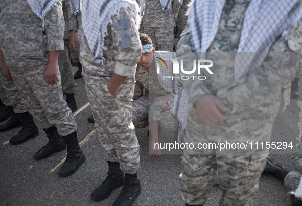 An Iranian schoolboy, who is also a member of the Basij paramilitary force, is looking on while waiting to march in a military parade markin...