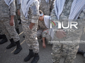 An Iranian schoolboy, who is also a member of the Basij paramilitary force, is looking on while waiting to march in a military parade markin...