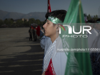 An Iranian schoolboy, who is also a member of the Basij paramilitary force, is standing at attention next to an Iranian flag as he prepares...