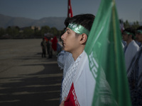 An Iranian schoolboy, who is also a member of the Basij paramilitary force, is standing at attention next to an Iranian flag as he prepares...