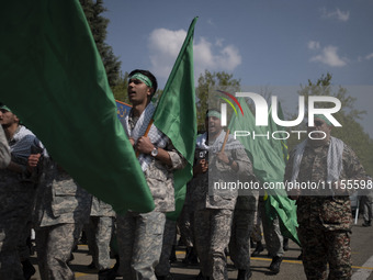 Members of the Basij paramilitary force are marching in a military parade to mark the anniversary of Iran's Army Day at an Army military bas...