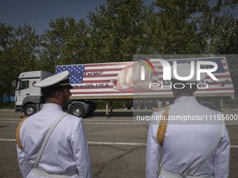 Two members of the Iranian navy are standing at attention as a truck carries a massive anti-U.S. billboard during a military parade marking...