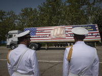 Two members of the Iranian navy are standing at attention as a truck carries a massive anti-U.S. billboard during a military parade marking...