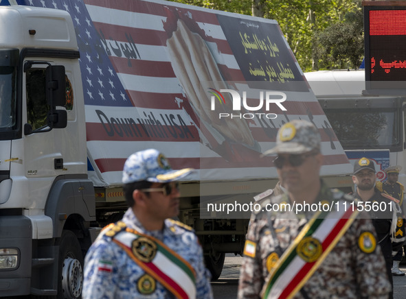 Members of the Iranian Army are standing under a massive anti-U.S. billboard after a military parade marking the anniversary of Iran's Army...