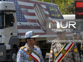 Members of the Iranian Army are standing under a massive anti-U.S. billboard after a military parade marking the anniversary of Iran's Army...