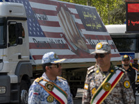 Members of the Iranian Army are standing under a massive anti-U.S. billboard after a military parade marking the anniversary of Iran's Army...