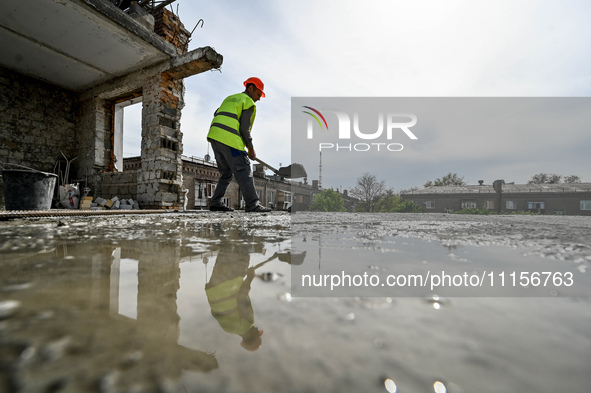 A worker with a spade is being reflected in a puddle while the residential building at 80 Nezalezhnoi Ukrainy Street/3 Yakova Novytskoho Str...