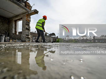 A worker with a spade is being reflected in a puddle while the residential building at 80 Nezalezhnoi Ukrainy Street/3 Yakova Novytskoho Str...