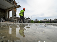 A worker with a spade is being reflected in a puddle while the residential building at 80 Nezalezhnoi Ukrainy Street/3 Yakova Novytskoho Str...