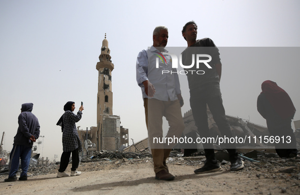 Palestinians are gathering around residential buildings that were destroyed during an Israeli raid, amid the ongoing conflict between Israel...