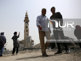 Palestinians are gathering around residential buildings that were destroyed during an Israeli raid, amid the ongoing conflict between Israel...