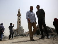 Palestinians are gathering around residential buildings that were destroyed during an Israeli raid, amid the ongoing conflict between Israel...