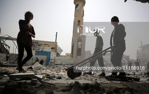 Palestinians are gathering around residential buildings that were destroyed during an Israeli raid, amid the ongoing conflict between Israel...