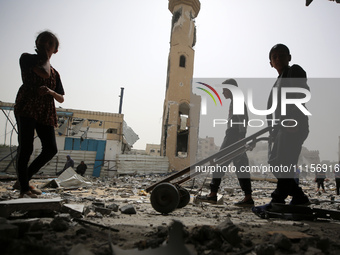 Palestinians are gathering around residential buildings that were destroyed during an Israeli raid, amid the ongoing conflict between Israel...