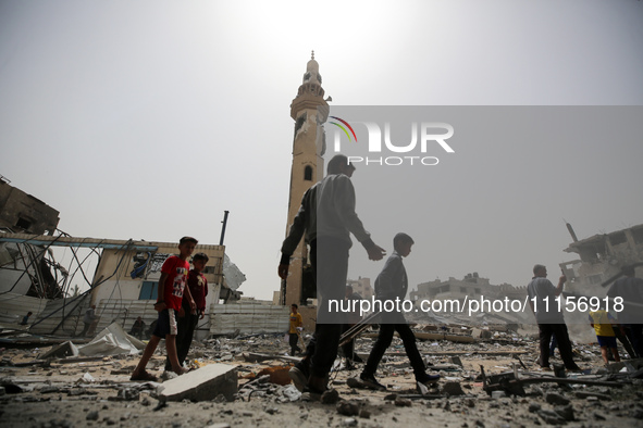 Palestinians are gathering around residential buildings that were destroyed during an Israeli raid, amid the ongoing conflict between Israel...