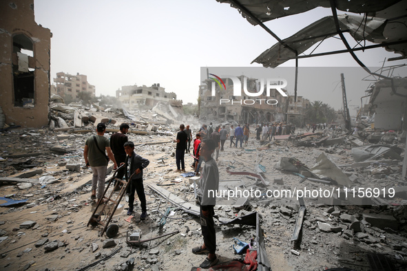 Palestinians are gathering around residential buildings that were destroyed during an Israeli raid, amid the ongoing conflict between Israel...