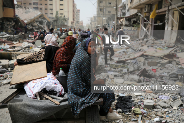 Palestinians are gathering around residential buildings that were destroyed during an Israeli raid, amid the ongoing conflict between Israel...