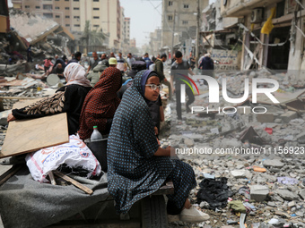 Palestinians are gathering around residential buildings that were destroyed during an Israeli raid, amid the ongoing conflict between Israel...