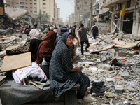 Palestinians are gathering around residential buildings that were destroyed during an Israeli raid, amid the ongoing conflict between Israel...