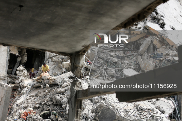 Palestinians are gathering around residential buildings that were destroyed during an Israeli raid, amid the ongoing conflict between Israel...