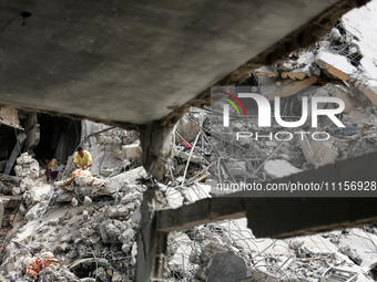 Palestinians are gathering around residential buildings that were destroyed during an Israeli raid, amid the ongoing conflict between Israel...