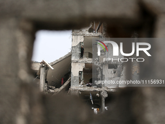 Palestinians are gathering around residential buildings that were destroyed during an Israeli raid, amid the ongoing conflict between Israel...