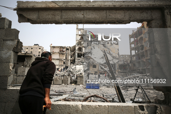 Palestinians are gathering around residential buildings that were destroyed during an Israeli raid, amid the ongoing conflict between Israel...