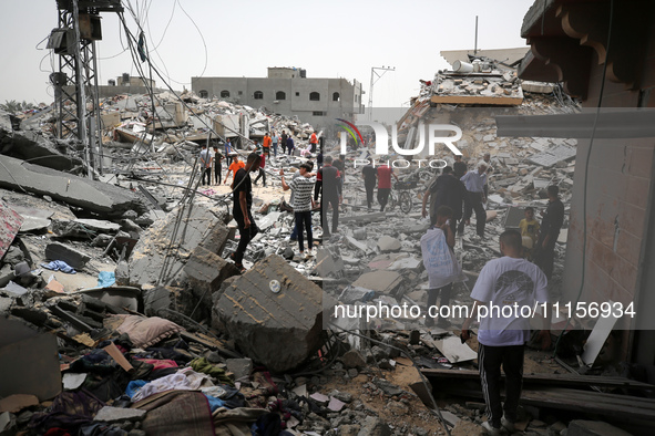 Palestinians are gathering around residential buildings that were destroyed during an Israeli raid, amid the ongoing conflict between Israel...