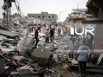 Palestinians are gathering around residential buildings that were destroyed during an Israeli raid, amid the ongoing conflict between Israel...