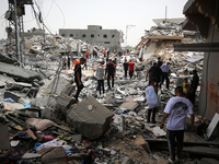 Palestinians are gathering around residential buildings that were destroyed during an Israeli raid, amid the ongoing conflict between Israel...