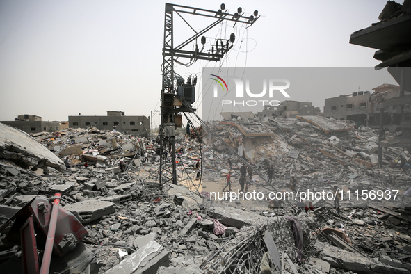 Palestinians are gathering around residential buildings that were destroyed during an Israeli raid, amid the ongoing conflict between Israel...