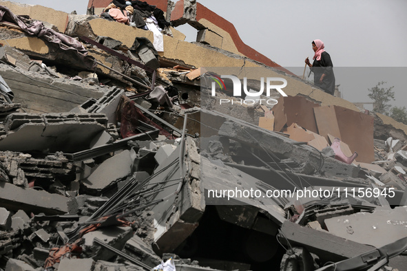 Palestinians are gathering around residential buildings that were destroyed during an Israeli raid, amid the ongoing conflict between Israel...