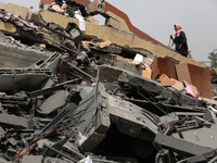 Palestinians are gathering around residential buildings that were destroyed during an Israeli raid, amid the ongoing conflict between Israel...