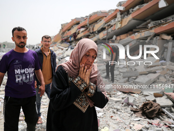 Palestinians are gathering around residential buildings that were destroyed during an Israeli raid, amid the ongoing conflict between Israel...