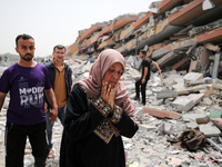 Palestinians are gathering around residential buildings that were destroyed during an Israeli raid, amid the ongoing conflict between Israel...