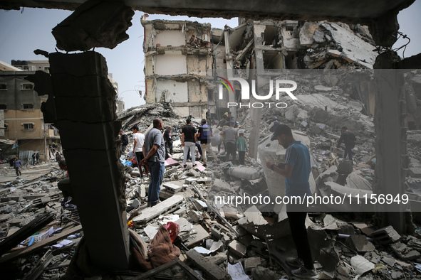 Palestinians are gathering around residential buildings that were destroyed during an Israeli raid, amid the ongoing conflict between Israel...