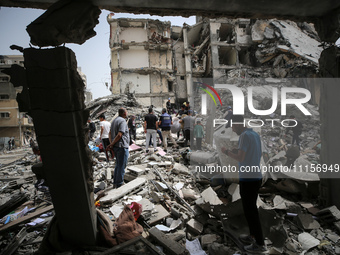 Palestinians are gathering around residential buildings that were destroyed during an Israeli raid, amid the ongoing conflict between Israel...