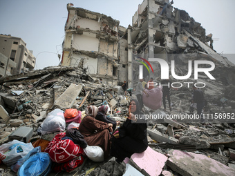 Palestinian women are reacting as they sit on the rubble of a residential building that housed their apartments, following an Israeli raid,...