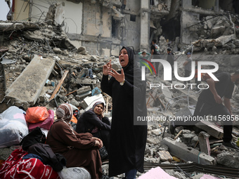 Palestinian women are reacting as they sit on the rubble of a residential building that housed their apartments, following an Israeli raid,...