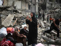 Palestinian women are reacting as they sit on the rubble of a residential building that housed their apartments, following an Israeli raid,...