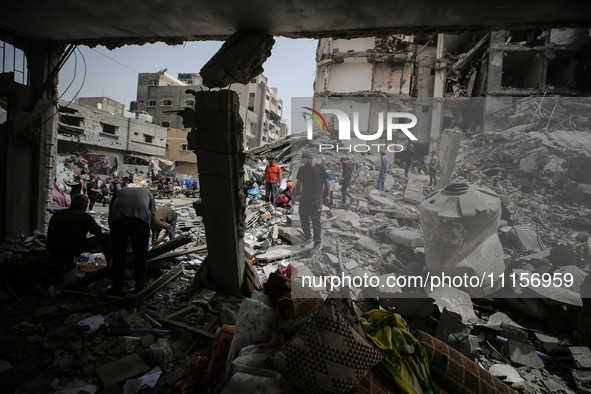 Palestinians are gathering around residential buildings that were destroyed during an Israeli raid, amid the ongoing conflict between Israel...