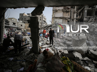 Palestinians are gathering around residential buildings that were destroyed during an Israeli raid, amid the ongoing conflict between Israel...