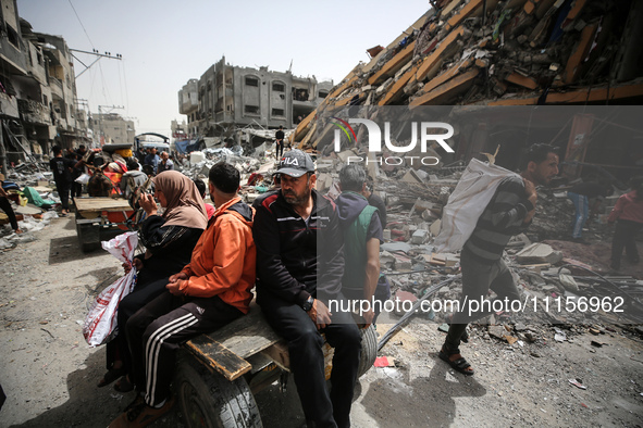 Palestinians are gathering around residential buildings that were destroyed during an Israeli raid, amid the ongoing conflict between Israel...