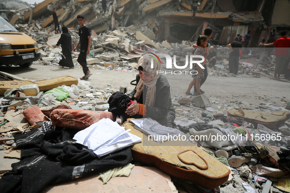 A Palestinian woman is searching for her belongings after her apartment was destroyed in an Israeli raid, amid the ongoing conflict between...