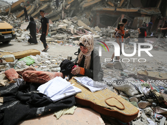 A Palestinian woman is searching for her belongings after her apartment was destroyed in an Israeli raid, amid the ongoing conflict between...