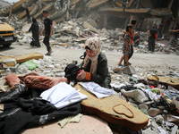 A Palestinian woman is searching for her belongings after her apartment was destroyed in an Israeli raid, amid the ongoing conflict between...