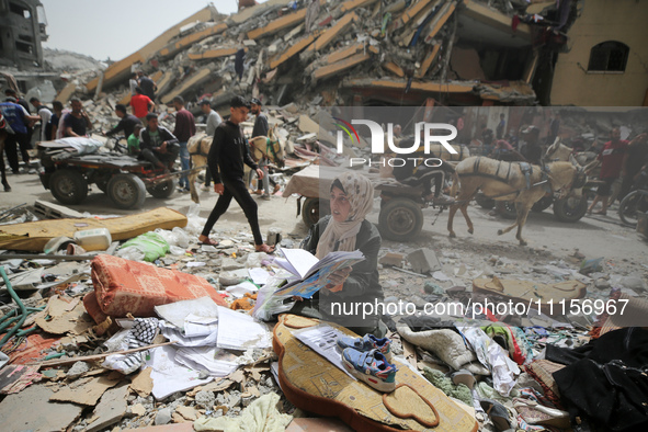 A Palestinian woman is searching for her belongings after her apartment was destroyed in an Israeli raid, amid the ongoing conflict between...