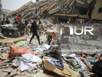 A Palestinian woman is searching for her belongings after her apartment was destroyed in an Israeli raid, amid the ongoing conflict between...